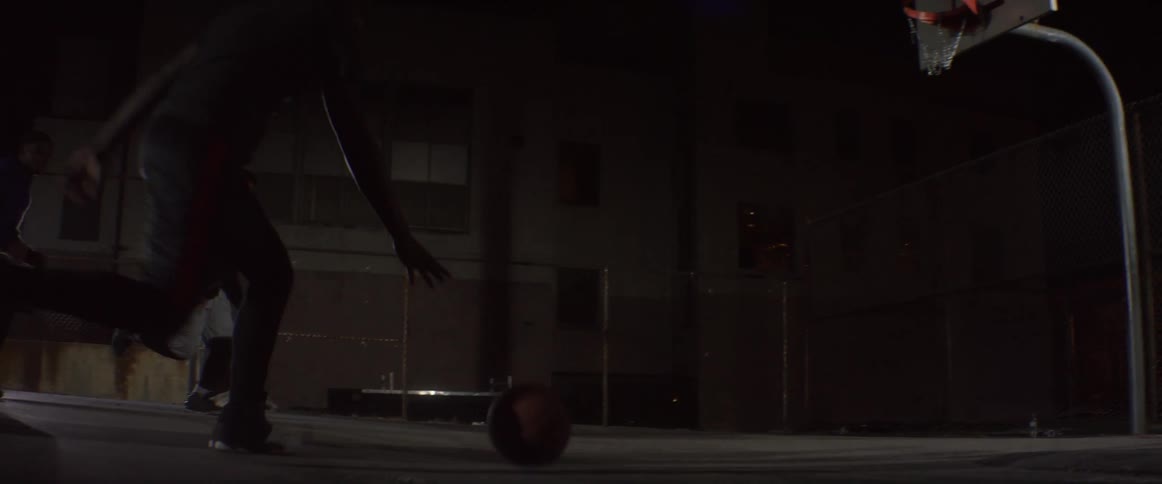 Men play basketball at night