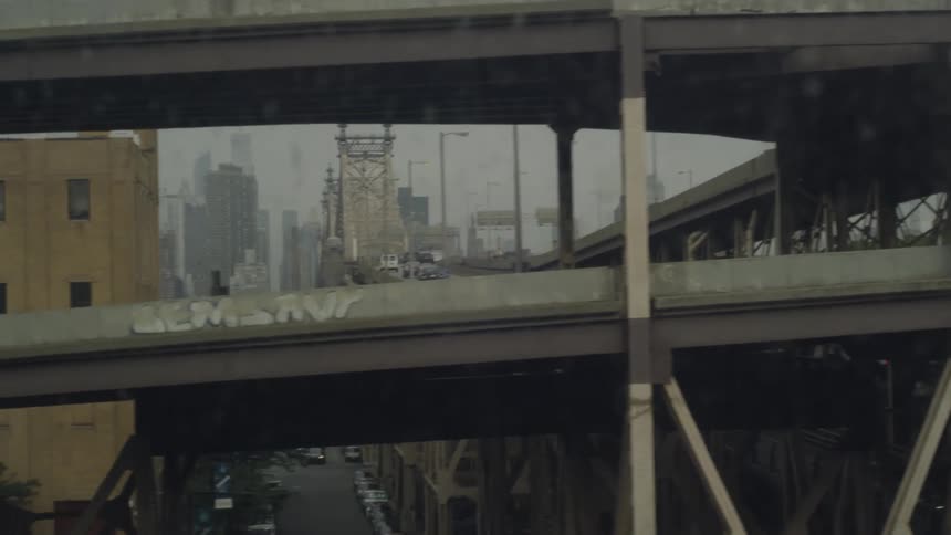 From a moving vehicle the camera sees a downtown urban bridge with grafitti on it