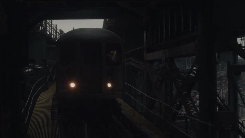 A train moving into a train station under a dark structure