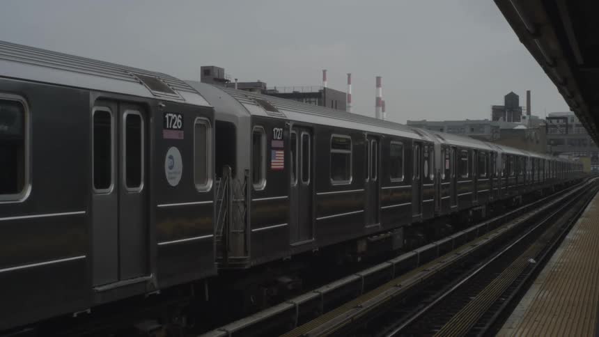 Passenger train slows to a stop at train station near factory