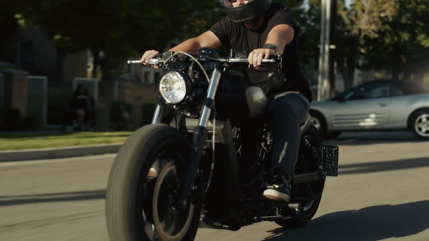 Man riding his motorcycle through a sunny residential neighborhood
