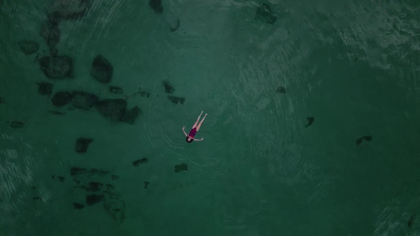 Woman peacefully floating in the lake gently moving her arms and relaxing