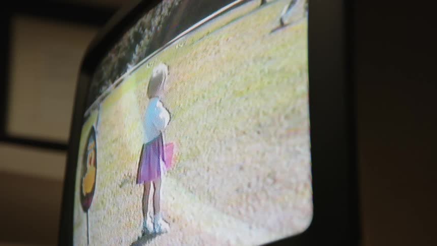 Shot of a video playing on a television screen of children playing outside