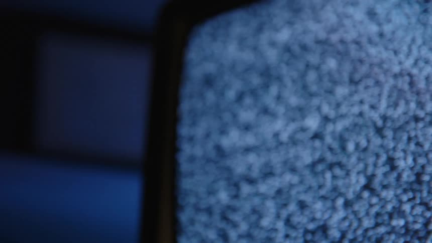 Static signal plays on screen of television in dark room