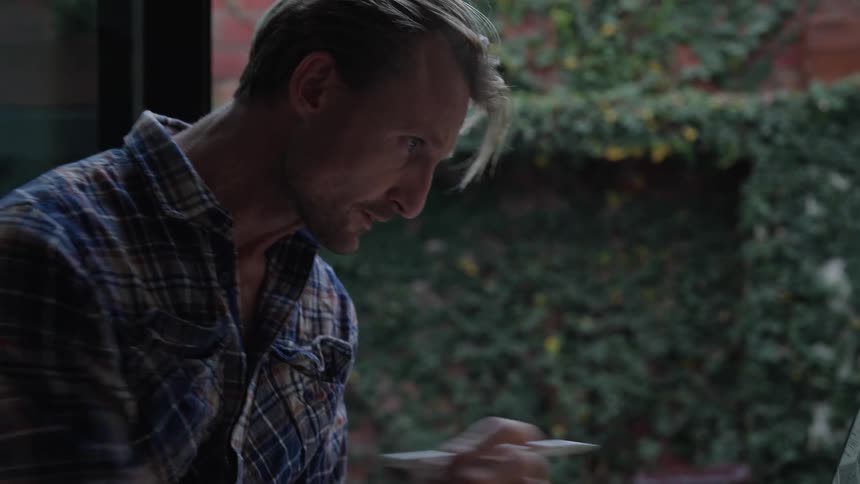 Man checks notebook while putting together a technical drawing on a tablet