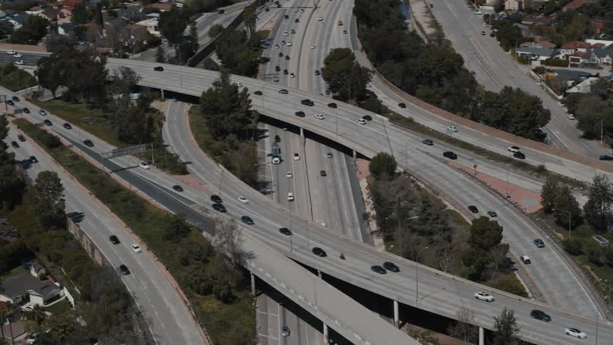 A drone shot reveals intersecting lanes of traffic traveling through Los Angeles