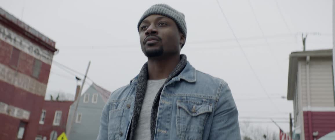 A man is walking outside wearing a hat