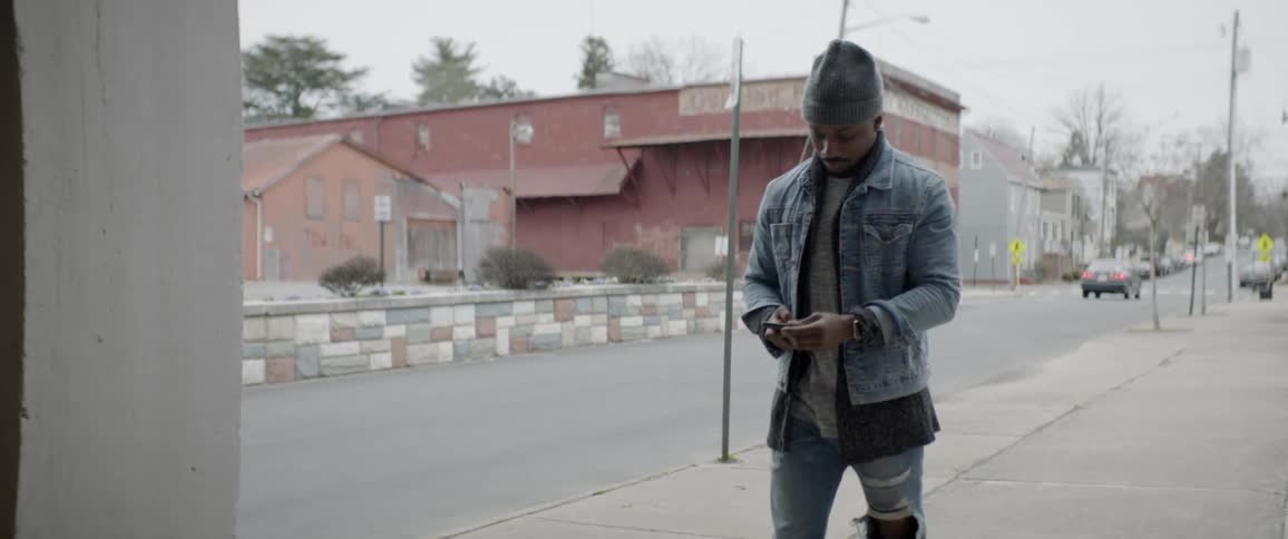 A man uses his phone while walking down the street