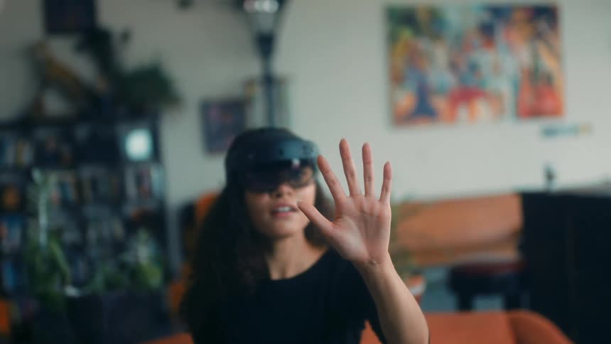 A woman is inside using virtual reality and moving her hand