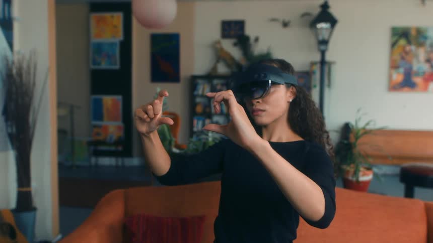 A woman wearing a virtual reality headset holds her hands out like shes using a camera