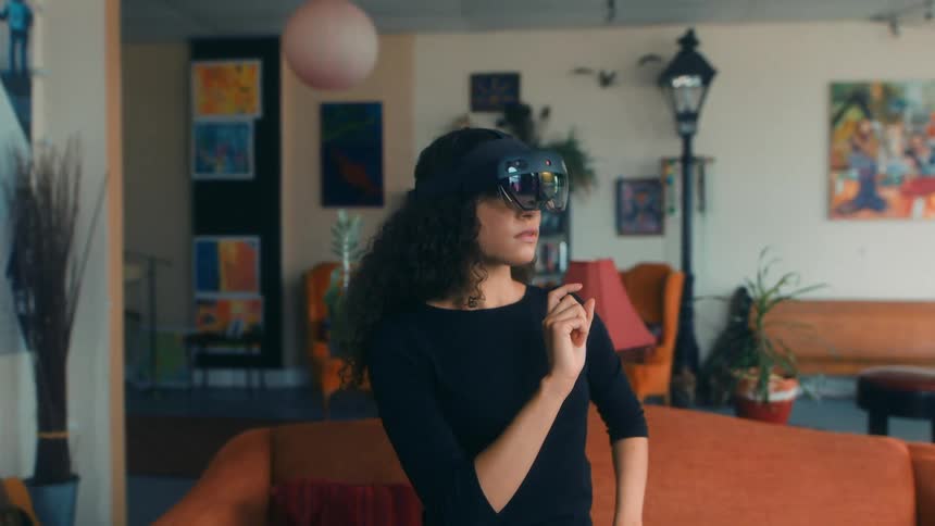 A woman uses a virtual reality headset in her apartment and touches the air like a touchscreen
