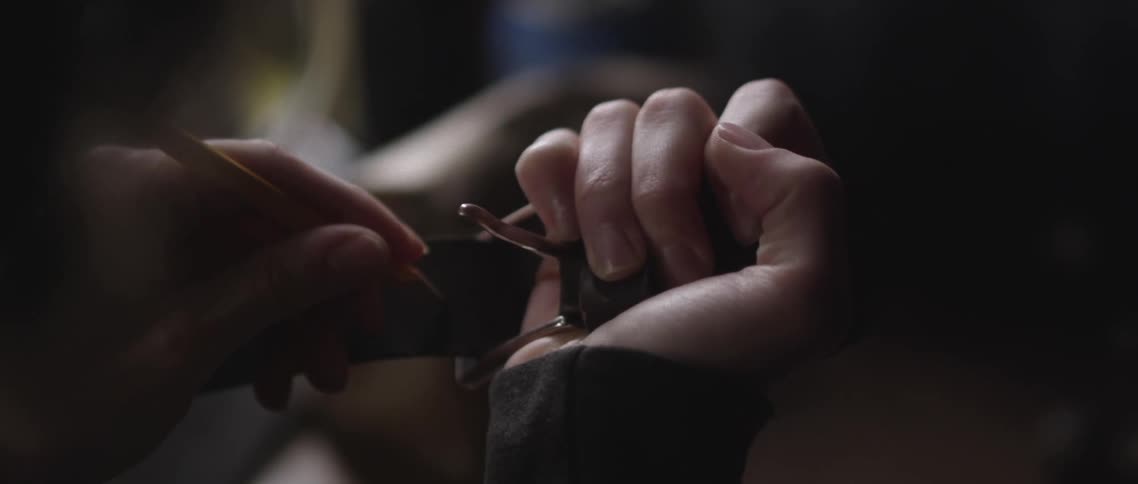 A person uses a pencil to mark a spot on a leather belt