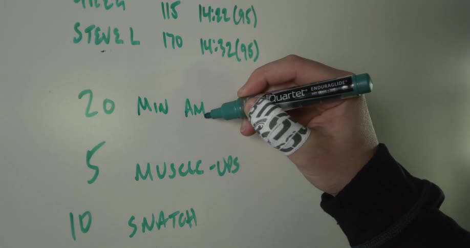 A hand writes a fitness routine on a whiteboard
