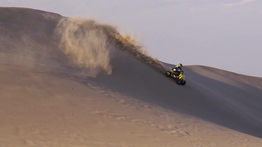 Someone riding an atv on the side of a sand dune