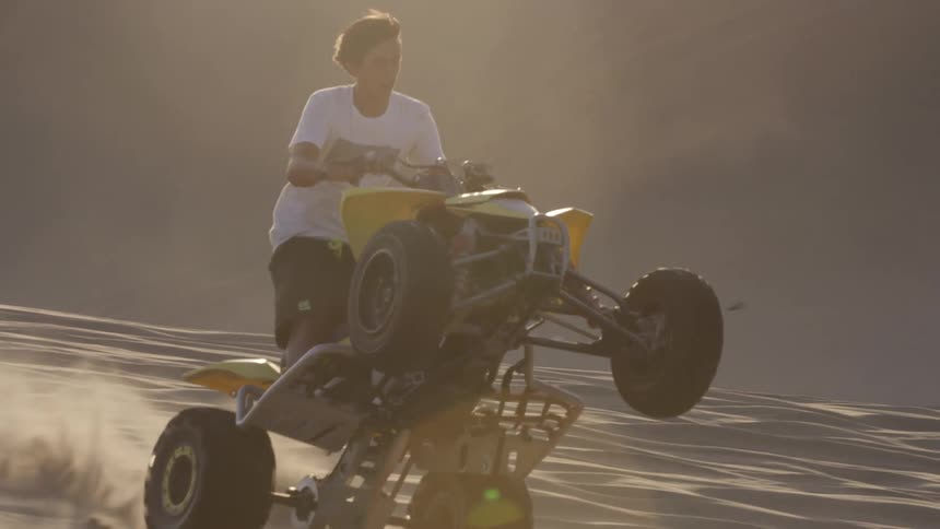 A man riding a quad and popping a wheelie