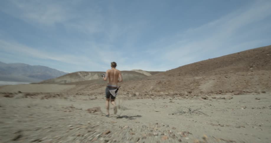 A man is racing along the desert carrying a camera