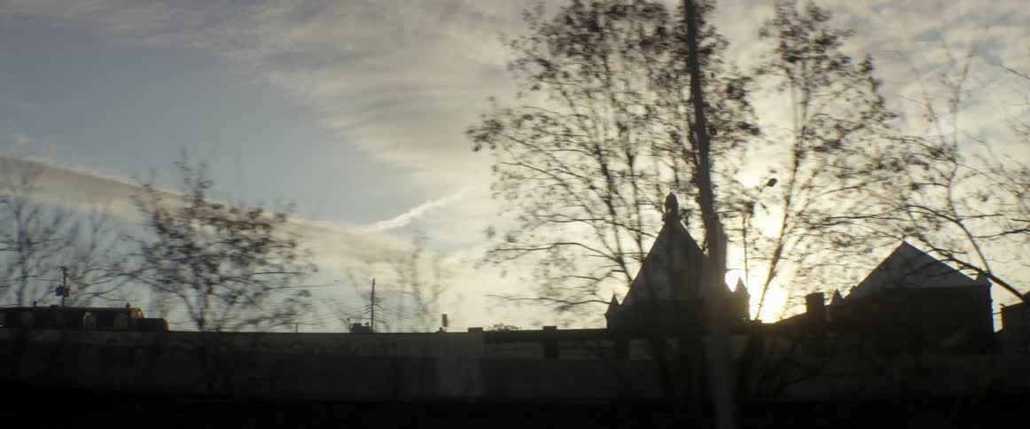 The sun is setting over a building lined with trees
