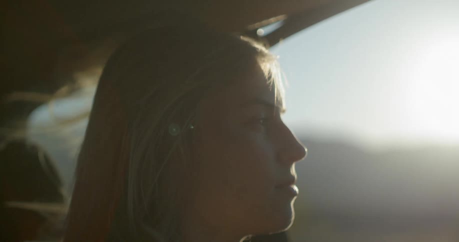 A woman is riding in a car wind blowing through her hair