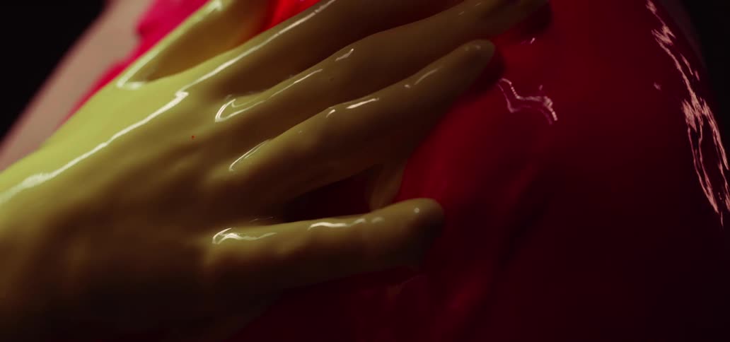A person with yellow paint on their hand rubbing their body with red paint