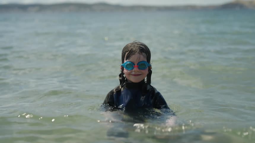 Girl with piggy tails swimming at the beach wearing swimming goggles