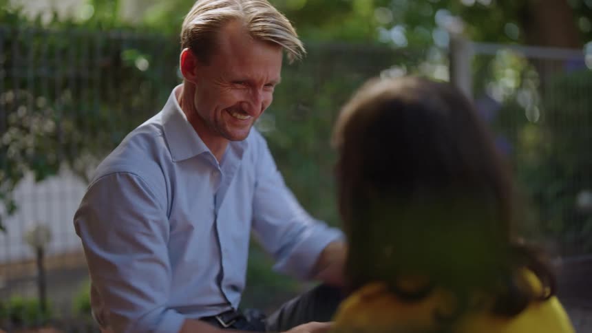 Father sitting outdoors together talking smile and high five
