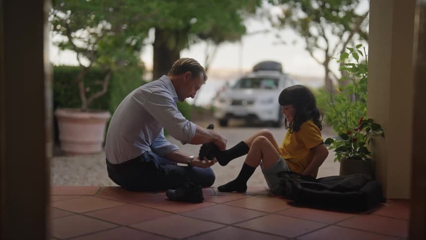 Father is helping his daughter put on her shoe and gives a high five when the shoe is put on