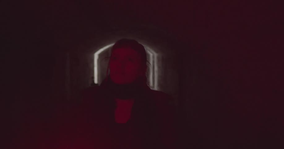 A woman walking down a dark corridor
