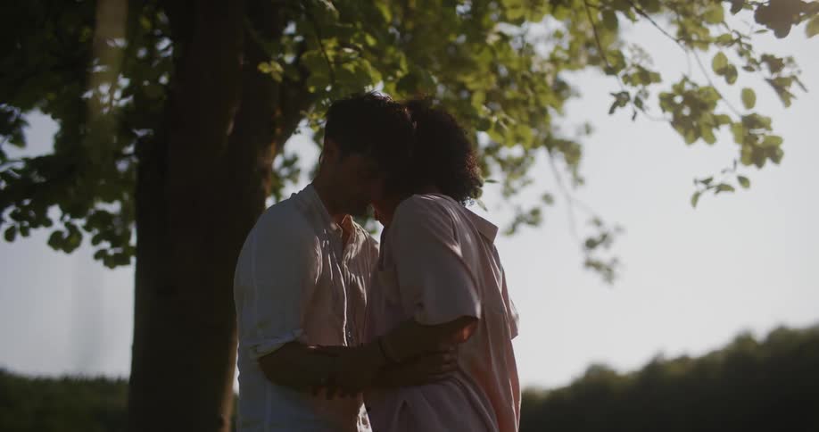 Man and woman hugging each other with a look of sadness in a forested landscape