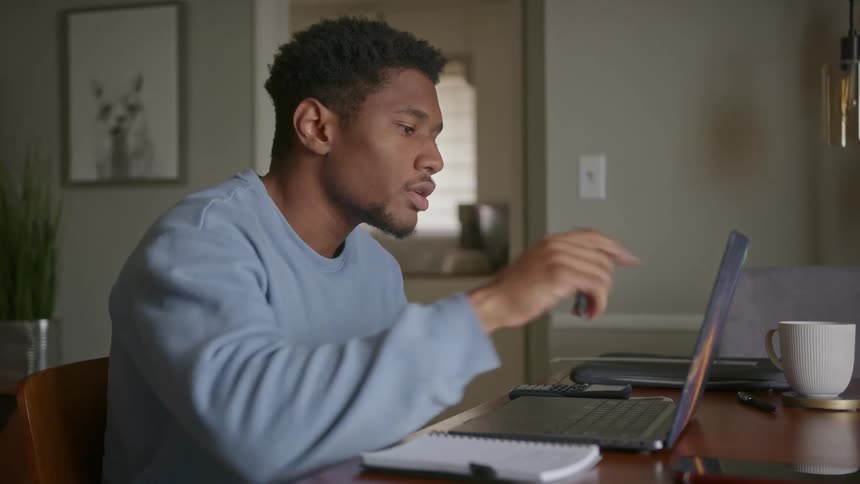 A man is sitting at a table with his laptop