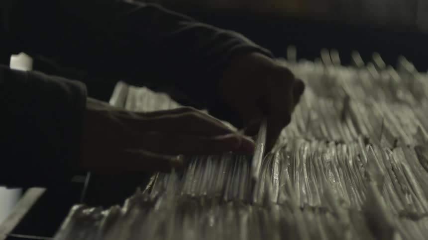 A clsoe up of a person looking through records that are wrapped in plastic