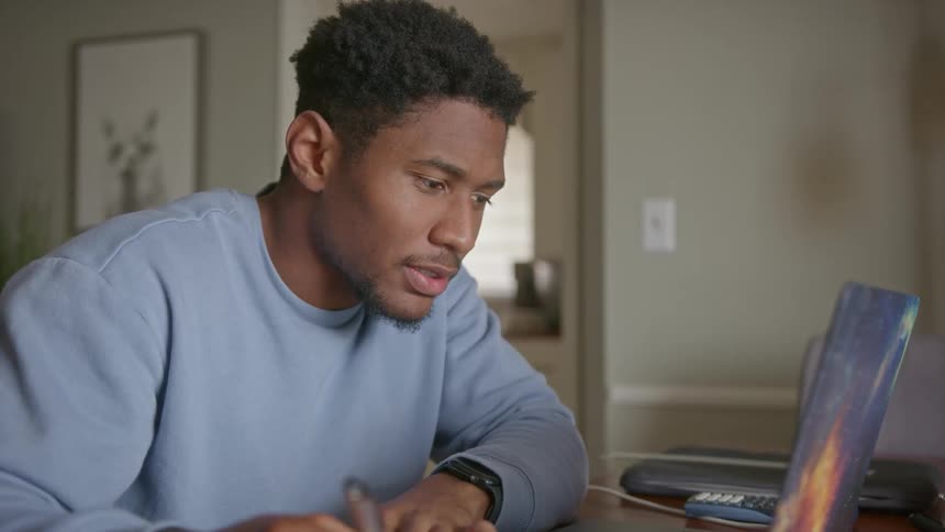 A man smiles and writes notes in his notebook