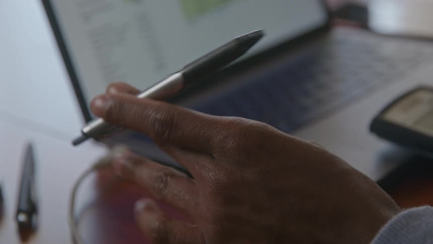 Anxious person tapping his pen on a wooden table