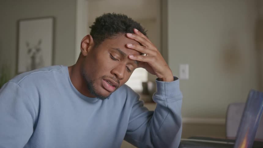 A man is thinking by his laptop