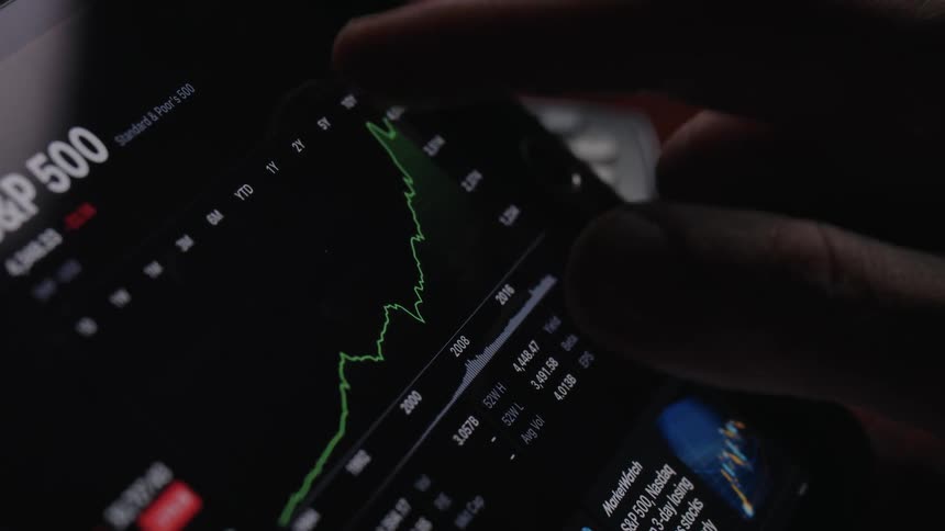 Man on a handheld tablet reading price graphs on the screen