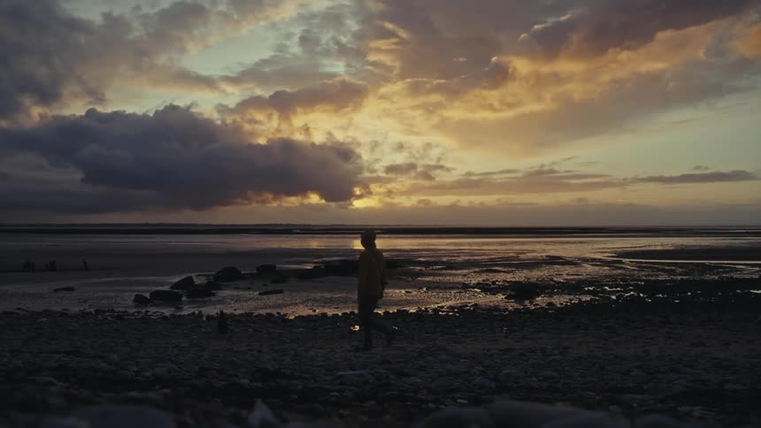 A man walks on the beach at dawn