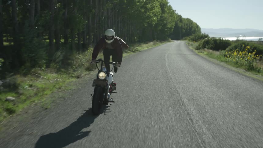 A man rides a motorcycle very fast and then stands up on the seat