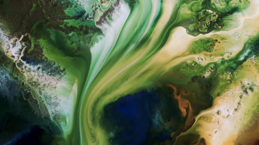 Liquid green and yellow and white flow through a textured surface blending as it moves