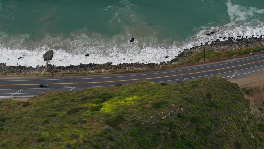 The PCH coastline is revealed with cars driving by
