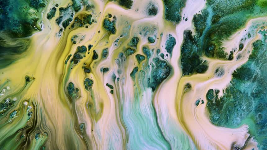 Yellow liquid flows down a green surface blending and becoming lighter as it moves