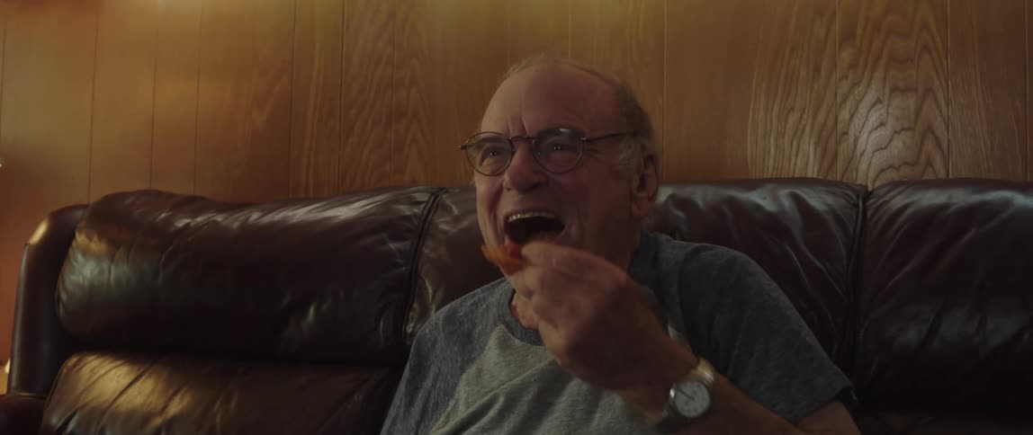 A man eats and cheers as he watches something