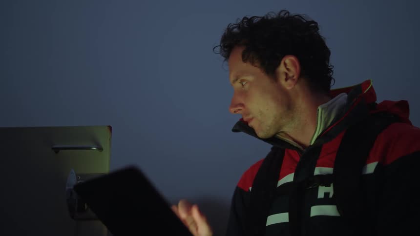 A man is using his tablet while trying to fix a machine