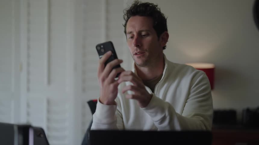 A man talks on his cell phone before turning back to his laptop