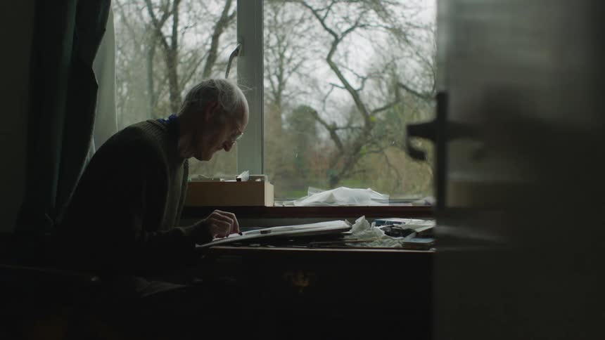 A man is writing at the table