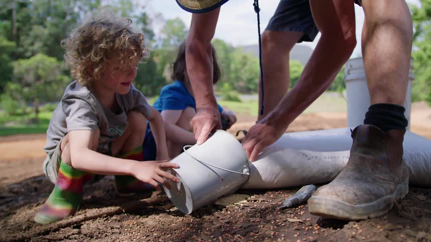 A father pours seeds into a bucket