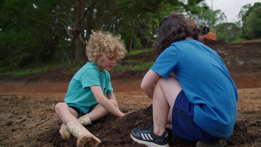 Two children dig in the dirt