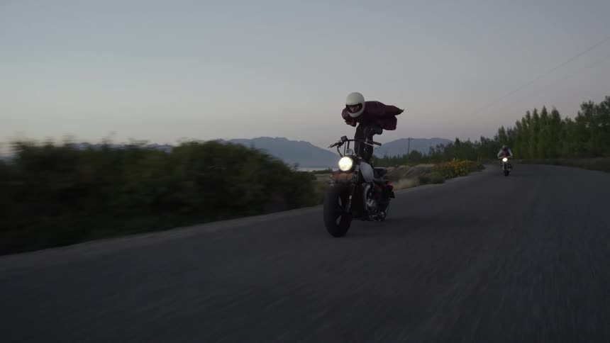 A motorcyclists performs a stunt by standing on his moving bike