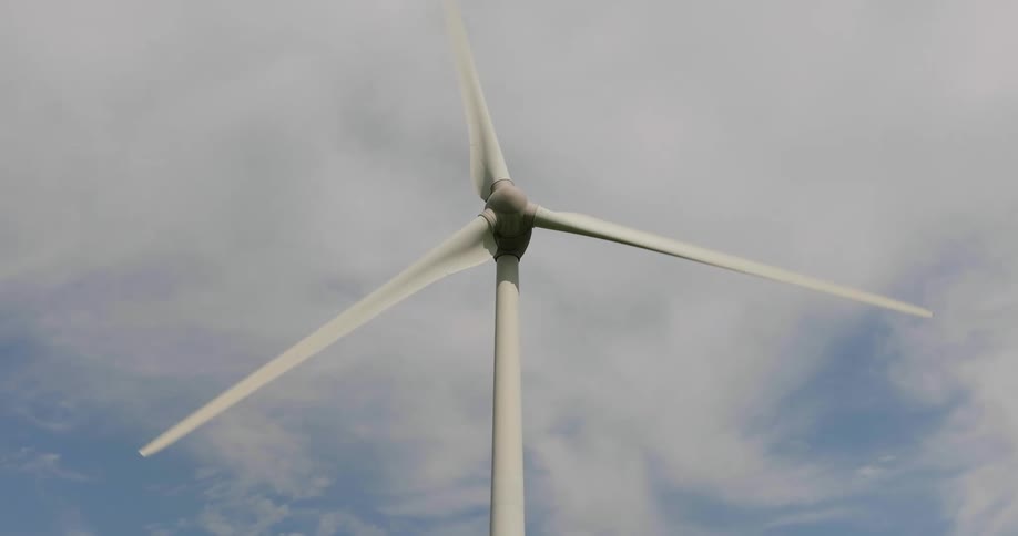 The blades of a wind turbine under a daytime sky