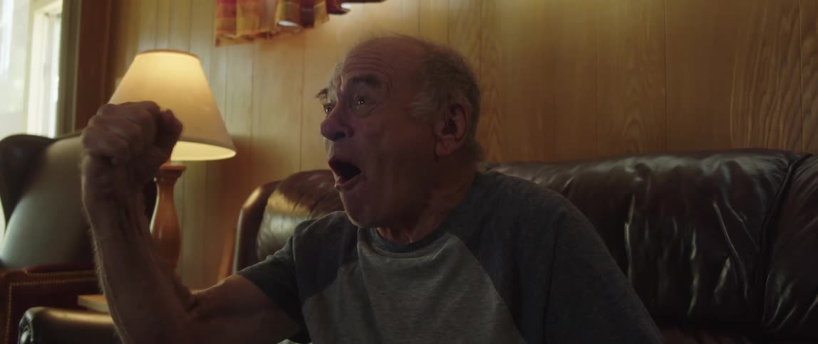 A man eats a snack while cheering at something
