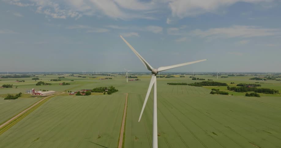 A wind turbine spinning above a vast grassland during the day