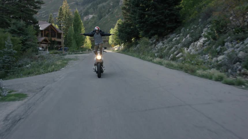 A man stands on his motorcycle while riding it